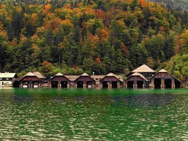 Berchtesgaden Travel Guide: Scenic Alpine lake with boathouses and autumn foliage in Germany.