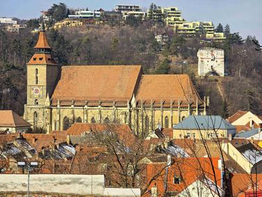Brasov, Romania. Iconic Black Church surrounded by medieval architecture and mountain backdrop.