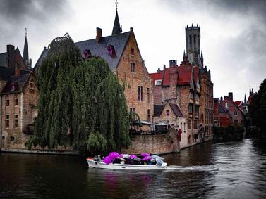Brugge, Belgium. Overcast view of a canal with a boat and medieval buildings.