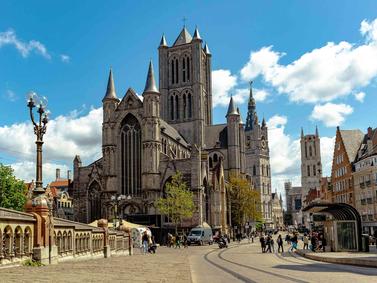 Ghent, Belgium. Daytime view of Saint Nicholas' Church with pedestrians and blue sky.