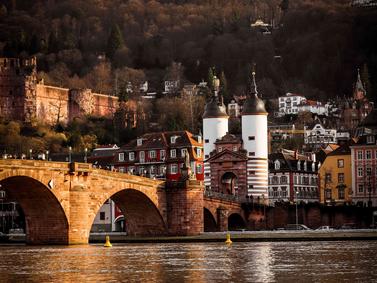 Heidelberg, Germany. Old Bridge gate towers against historical buildings at dusk.