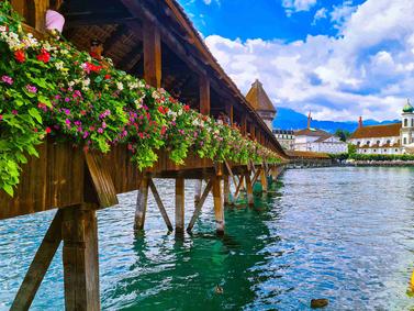 Chapel Bridge in Lucerne with flowers and Mount Pilatus in the background.