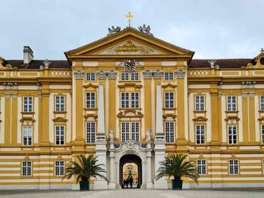 Melk Travel Guide: The distinctive yellow Baroque facade of Melk Abbey overlooking the Danube River.