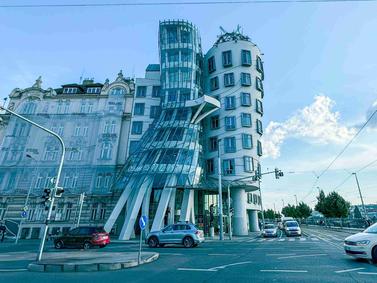 The Dancing House in Prague, a famous modern architectural landmark set along the Vltava River, contrasting with historic city buildings