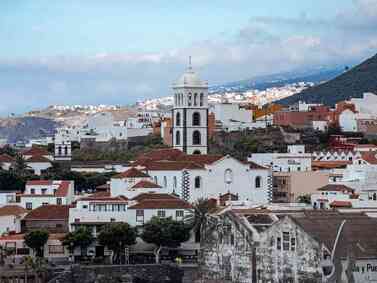 Spain: Whitewashed buildings and bell tower with lush hills in the background.