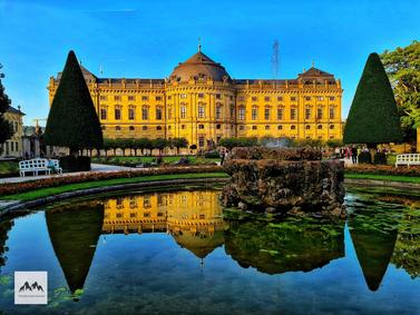 Würzburg, Germany. Würzburg Residence with reflection in pond, clear blue sky.