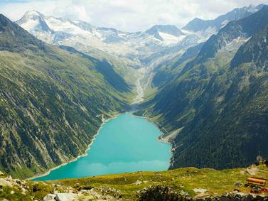 Zillertal: Scenic view from Olpererhütte, showcasing the Alps and the famous panorama bridge under clear skies.